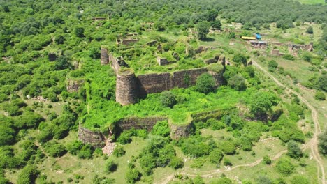 Toma-Aérea-De-Un-Antiguo-Fuerte-O-Castillo-Abandonado-Y-Cubierto-De-Un-Espeso-Bosque-Verde-En-Gwalior-Madhya-Pradesh,-India