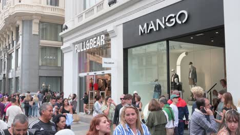 Una-Calle-Concurrida-Con-Compradores-Y-Peatones-Pasando-Por-La-Multinacional-Española-De-Diseño-De-Ropa-De-Inditex,-Pull-And-Bear-Y-Tiendas-Mango-En-España.