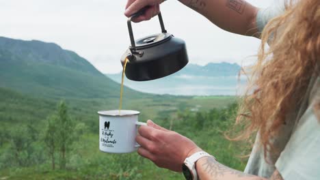 Frau-Gießt-Kaffee-Aus-Einem-Wasserkocher-In-Eine-Tasse-Im-Freien---Nahaufnahme