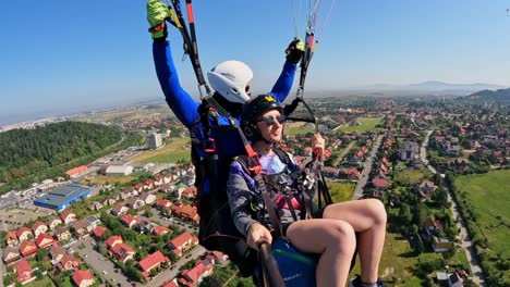 In-the-picturesque-city-of-Brasov,-Romania,-a-female-parachutist-and-her-instructor-are-embarking-on-a-thrilling-aerial-adventure