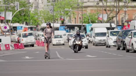 Mujer-Joven-Montando-Bicicleta-Eléctrica-A-Través-Del-Tráfico-En-Madrid