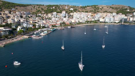 Yachts-and-Boats-Floating-in-the-Bay,-Adorned-by-Cityscape,-Harbor,-and-Hotels-for-a-Memorable-Summer-Holiday,-Saranda-Seaside-Elegance