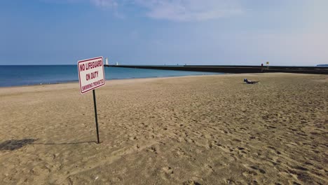 No-Lifeguard-sign-on-an-empty-beach-at-Sodus-point-New-York-vacation-spot-at-the-tip-of-land-on-the-banks-of-Lake-Ontario