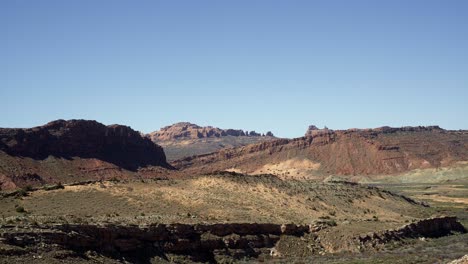 Small-tilt-up-shot-of-a-dry-desert-wide-landscape-scene-in-southern-Utah-with-hills-and-jagged-cliffs-on-a-warm-sunny-summer-day