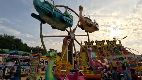 Sunset-time-scene,-colorful-rounding-animal-ride-in-amusement-park-with-little-kids-having-fun