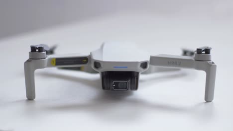 Dji-Mini-2-Sobre-Una-Mesa-En-Una-Vista-Frontal,-Con-El-Led-Frontal-Parpadeando-Encendido