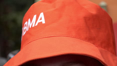 A-person-turns-their-head-while-wearing-an-orange-British-Medical-Association-hat-in-slow-motion
