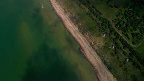 Aerial-drone-top-down-view-of-a-beach-coast-next-to-a-green-landscape