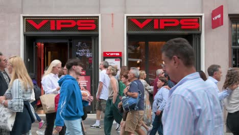 People-walk-past-the-Vips,-a-casual-full-service-restaurant-chain-on-a-crowded-street-in-Madrid,-Spain