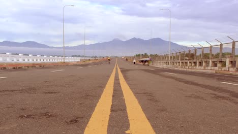 Eine-Weitwinkelstraße-Mit-Einer-Gelben-Linie-Und-Radfahrern-Im-Hintergrund