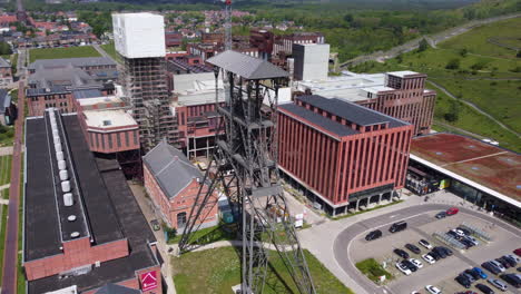 Aerial-circling-metallic-headframe-and-buildings-in-beMINE-Beringen,-Belgium