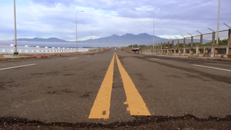 Una-Carretera-De-Cuatro-Carriles-Con-Solo-Ciclistas-Y-Montañas-Al-Fondo