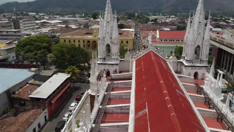 Flyover-red-metal-roof-to-tall-gothic-spires-of-Santa-Ana-Cathedral