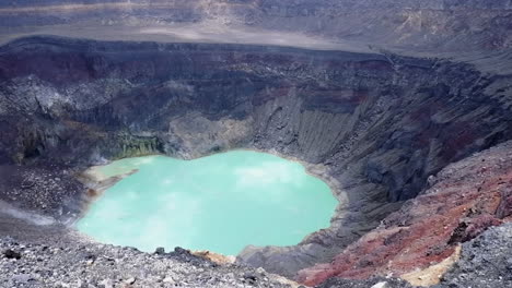 Pan-across-volcano-crater,-steaming-hot-lake-in-bottom-of-caldera