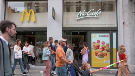 La-Gente-Pasa-Junto-A-La-Cadena-Multinacional-Estadounidense-De-Restaurantes-De-Hamburguesas-De-Comida-Rápida,-McDonald&#39;s,-Y-Su-Logotipo.