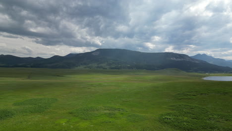 Grass-Valley-with-Lake-and-Looming-Mountains-and-Ominous-Clouds