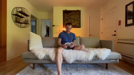 A-man-sits-in-his-apartment-reading-a-book-relaxingly