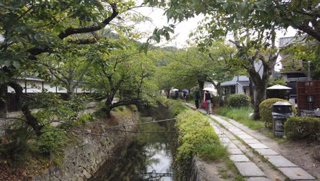 Im-Sommer-Gehen-Menschen-Mit-Regenschirmen-Auf-Dem-Philosophenweg-In-Kyoto,-Japans-Berühmtem-Reiseziel,-Spazieren