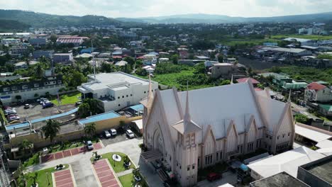 Cinematic-flyover-drone-shot-of-white,-pristine-church-located-in-bustling,-provincial-town