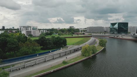 Drone-descends-above-River-Spree,-cloudy-day-in-Berlin,-Germany