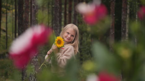 Handheld-slow-motion-shot-of-a-little-blonde-girl-smiling-and-showing-a-flower-in-the-Finnishvh-countryside-on-a-sunny-autumn-day