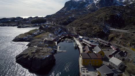 Aerial-shot-of-the-famous-fishing-village-Nusfjord-in-Lofoten-Norway-on-a-bright-sunny-winter's-day-tucked-into-the-rocky-coastal-mountains