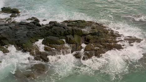 Filmische-Luftaufnahme-In-Zeitlupe-Von-Wellen,-Die-über-Die-Felsige-Küste-Von-Looc-Beach-In-Der-Stadt-Surigao,-Philippinen,-Strömen