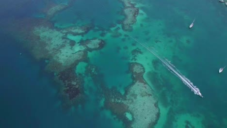 Barco-Pasando-Por-El-Agua-De-Mar-Turquesa-Sobre-Un-Arrecife-De-Coral-Tropical