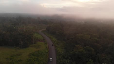 Vista-Aérea-De-Automóviles-Circulando-Por-La-Carretera-A-Través-De-Una-Jungla-Salvaje-Y-Brumosa-En-Ecuador