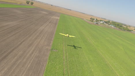 FPV-Drone-View-of-Small-Crop-Duster-Plane-Skimming-Low-Over-Rural-Grass-Runway