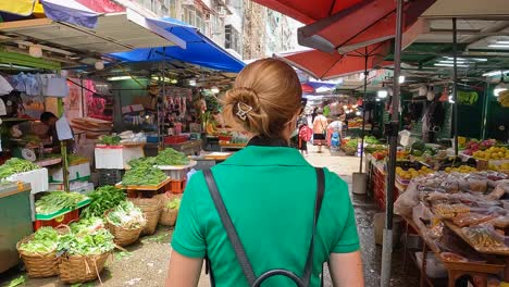 POV-Walking-Behind-Female-Tourist-Wearing-Green-Dress-With-Backpack-Through-Markets-At-Mong-Kok,-Hong-Kong