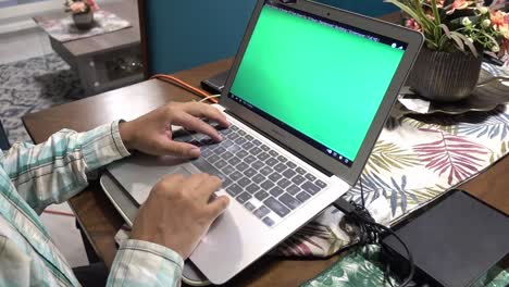 Ein-Mann,-Der-Das-Trackpad-Und-Die-Tastatur-Eines-Laptops-Mit-Grünem-Bildschirm-Verwendet