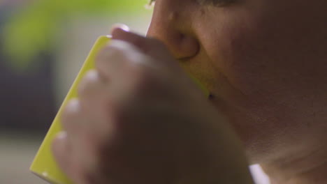 Close-Up-Shot-Of-A-Male-Caucasian-Blowing-His-Hot-Coffee-On-A-Yellow-Mug-And-Drinking-It-Afterwards