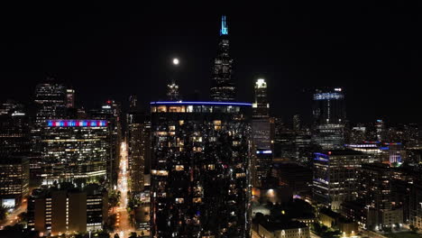 Vista-Aérea-Acercándose-A-Un-Condominio-De-Lujo-Con-Luna-Llena,-Fondo-Del-Horizonte-De-Chicago