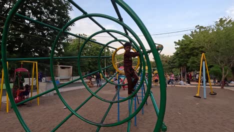 Little-child-playing-on-exercise-equipment-in-public-park-during