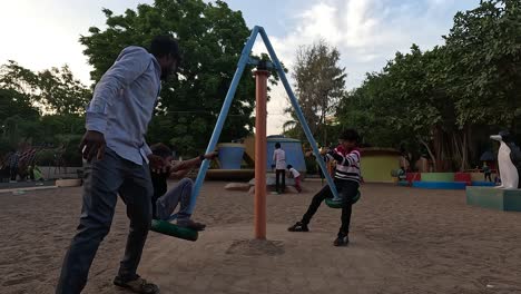 A-father-amuses-his-two-children-by-spinning-them-on-a-ride-in-a-public-park