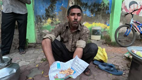 A-man-enjoys-sitting-on-the-ground-and-eating-corn-on-the-ground-during-a-holiday