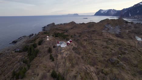 Aerial-orbit-drone-shot-of-a-old-Norwegian-historical-lighthouse-in-Lofoten-with-the-famous-village-Sorvagen-in-the-background