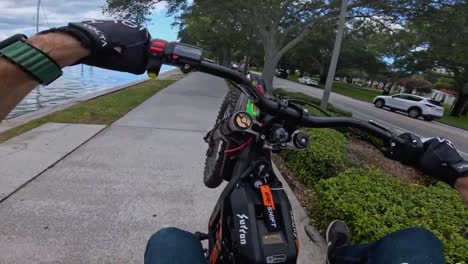 FPV-stunts-on-the-bike,-adventurous-man-performing-wheelies-on-the-sidewalk-near-traffic