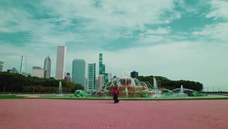 Aerial-Chicago,-Tracking-Around-Buckingham-Fountain,-tourists-walking,-Skyscrapers-In-The-Background