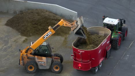 JCB-telehandler-dumping-silage-into-TRIOLIET-forage-silage-mixer-for-animal-feed