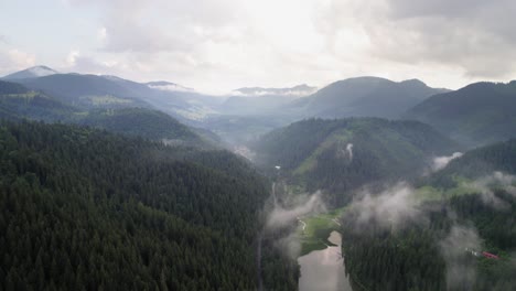 Berglandschaft-Mit-Tief-Hängenden-Wolken,-Kleines-Dorf-Und-See-Im-Blick