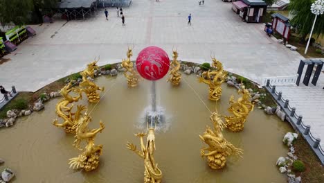 Golden-dragon-water-fountain-aerial-tilt-down-view-revealing-chinese-people-and-huaxiacheng-gate