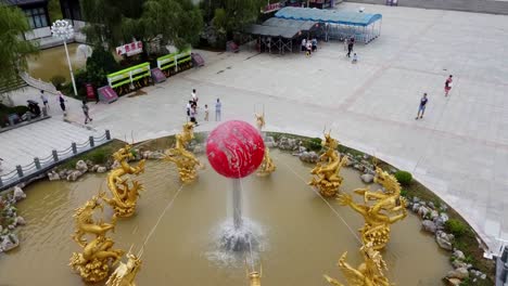 Filmische-Luftumlaufbahn,-Rechte-Ansicht-Des-Wasserbrunnens-Mit-Goldenen-Drachen-Im-Traditionellen-Chinesischen-Stil