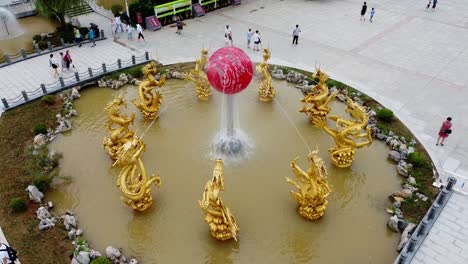 Traditionelle-Eingekreiste-Chinesische-Goldene-Drachenskulptur,-Wasserbrunnen,-Stationäre-Luftaufnahme,-Stadt-Weihai