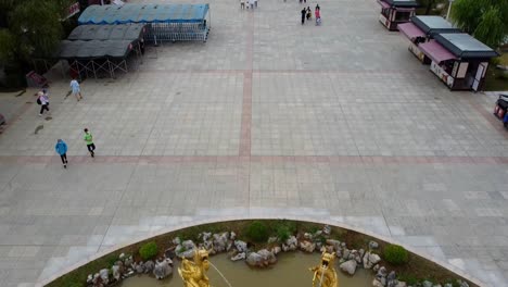 Golden-colored-dragons-water-fountain-aerial-bird's-eye-tilt-down-view-with-Chinese-gate-background