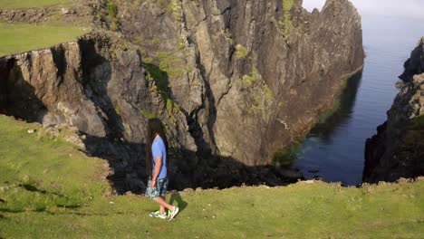 Cinematic-tracking-shot-of-a-man-walking-on-a-cliff's-edge