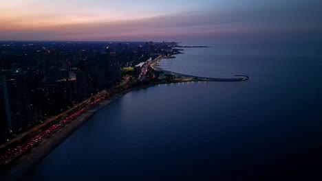 Chicago-USA-at-Twilight,-Aerial-View-of-Lake-Michigan-Coastline-and-City-Lights-Under-Purple-Sunset-Sky