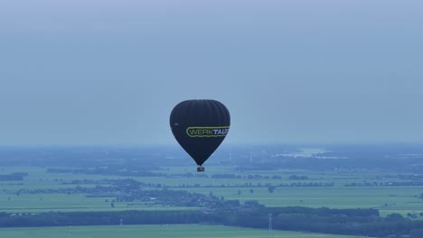 Hintergrund-Des-Blauen,-Dunstigen-Himmels-Steigt-Ein-Heißluftballon-Mit-Firmenbotschaft-Herab