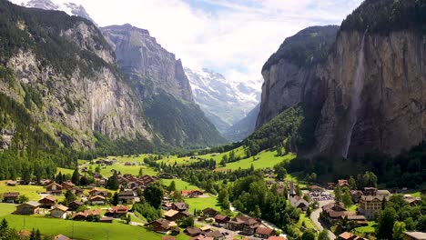 Swiss-Village-of-Lauterbrunnen-valley-amid-green-alpine-meadows,-Staubbach-waterfall,-snow-covered-mountain-Peaks